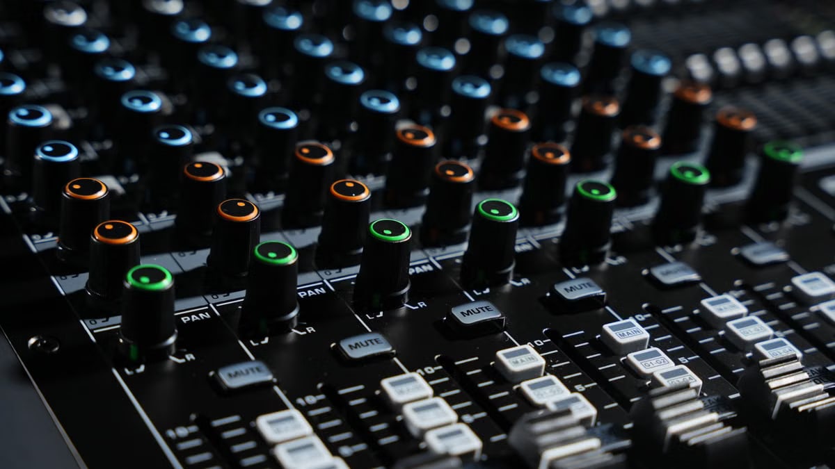 Detailed view of an audio mixing console with colorful lights in a professional studio setting.
